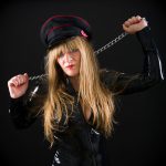 serious mistress wearing black rubber outfit holding a whip